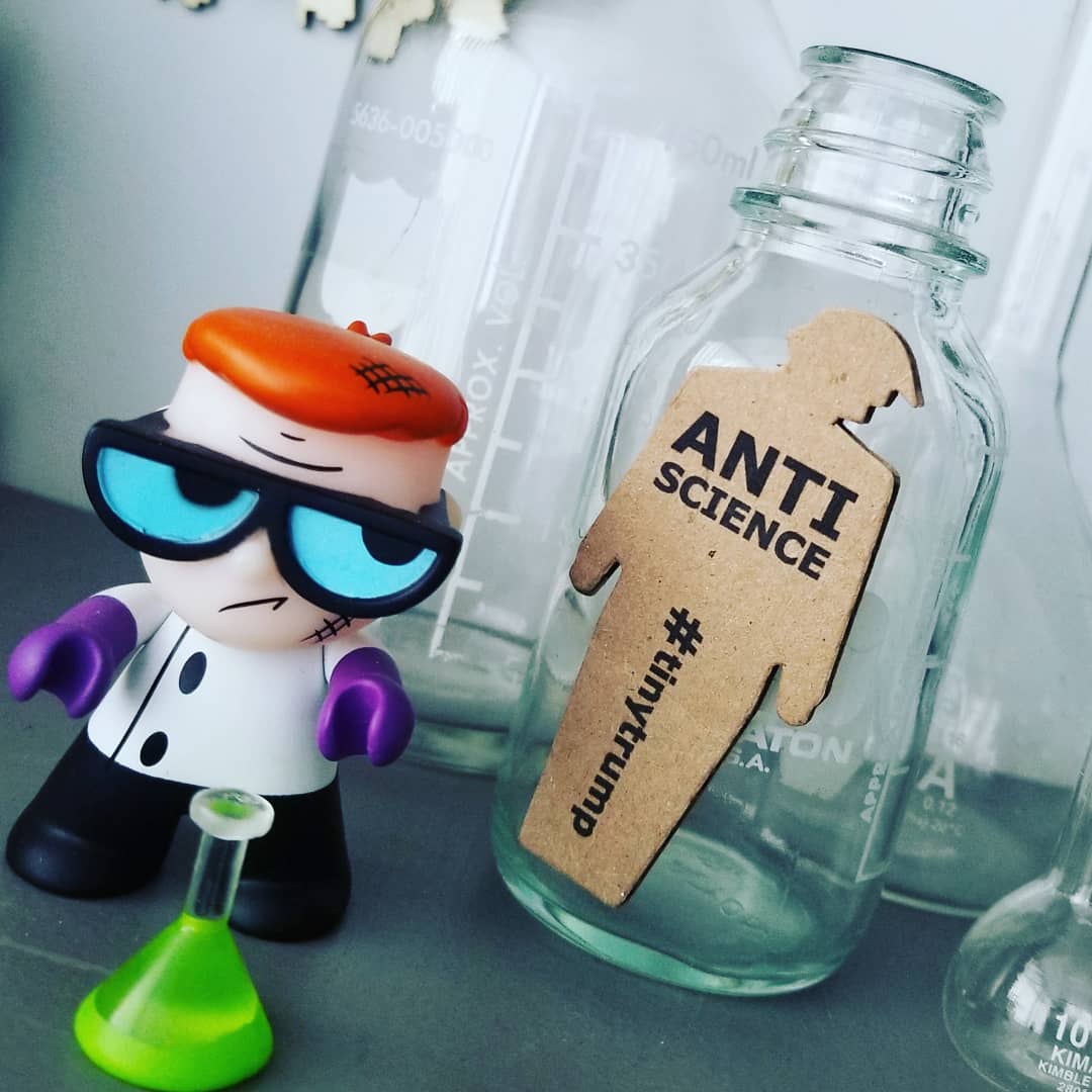 tiny trump with an 'Anti Science' slogan posed next to a Dexter's Labatory figure