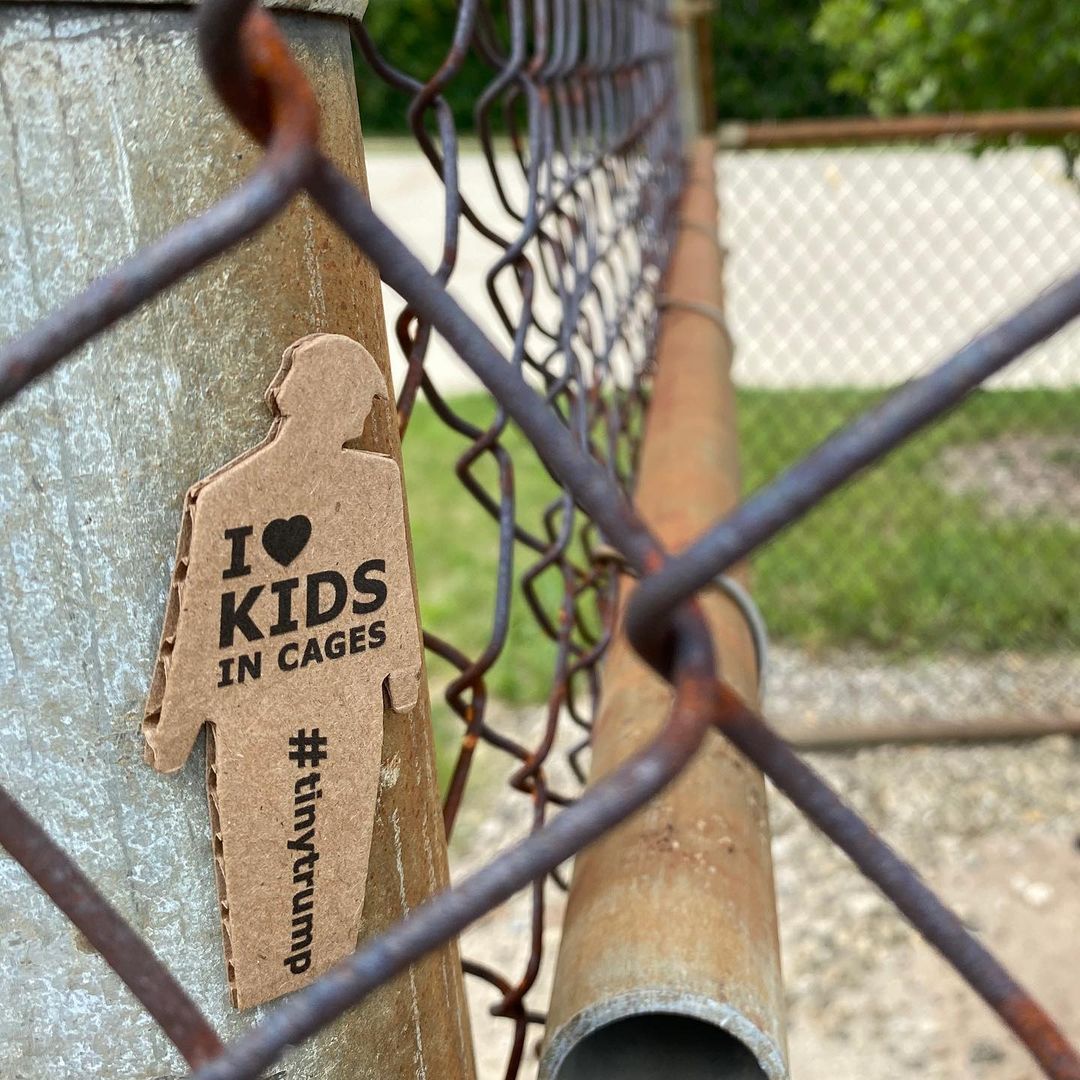 tiny trump with the stamp 'I Love Kids in Cages' taken against a chain linked fence 
